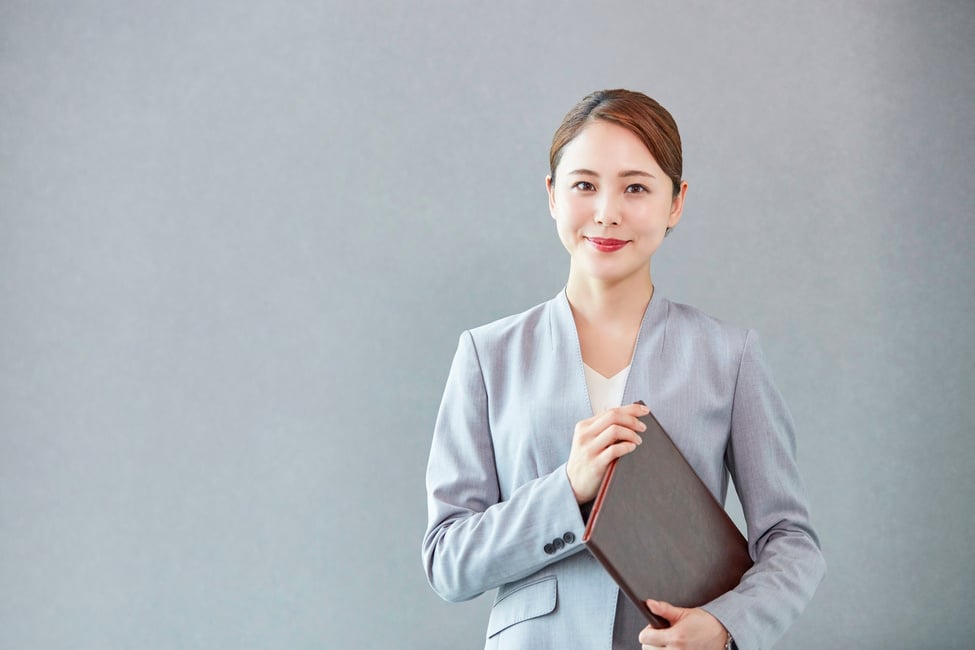 Confident Businesswoman in a Gray Suit Holding a Portfolio